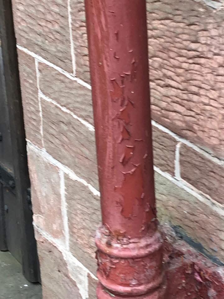 Traditional cast-iron drainpipe restoration on a stone church